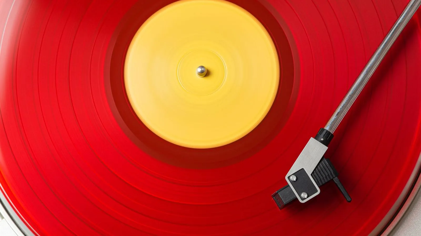 Disco de vinilo rojo con etiqueta amarilla girando en un tocadiscos, visto desde arriba